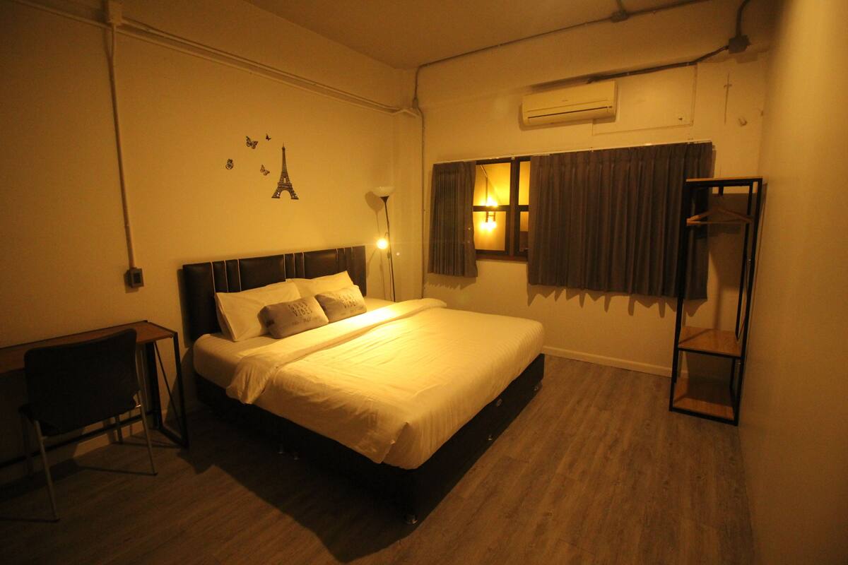 A hotel room with a bed, bedside table, lamp, and a wardrobe.