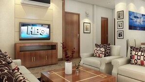 Una sala de estar moderna con televisor de pantalla plana, muebles de madera y una mesa de centro con objetos decorativos.