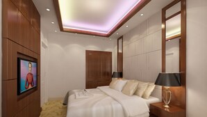 Una habitación de hotel moderna con una cama grande, mesitas de noche, un televisor montado en la pared y un armario de madera.