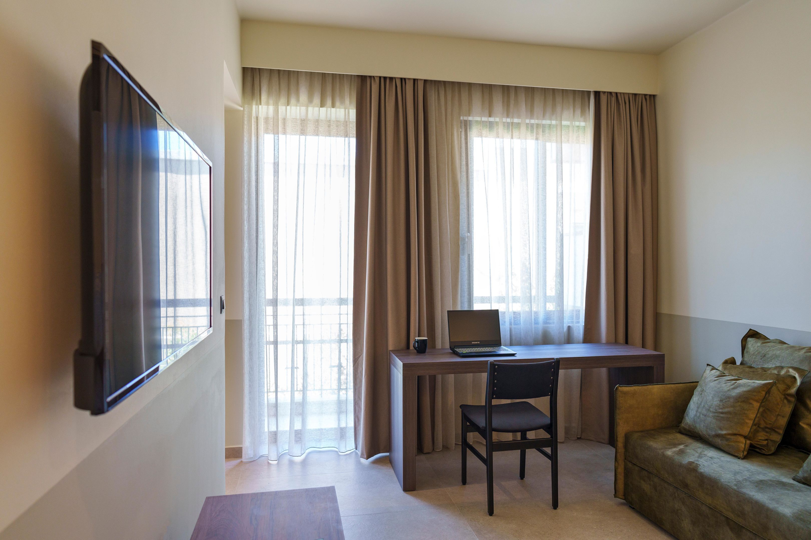 A room with a desk, chair, and a sofa.