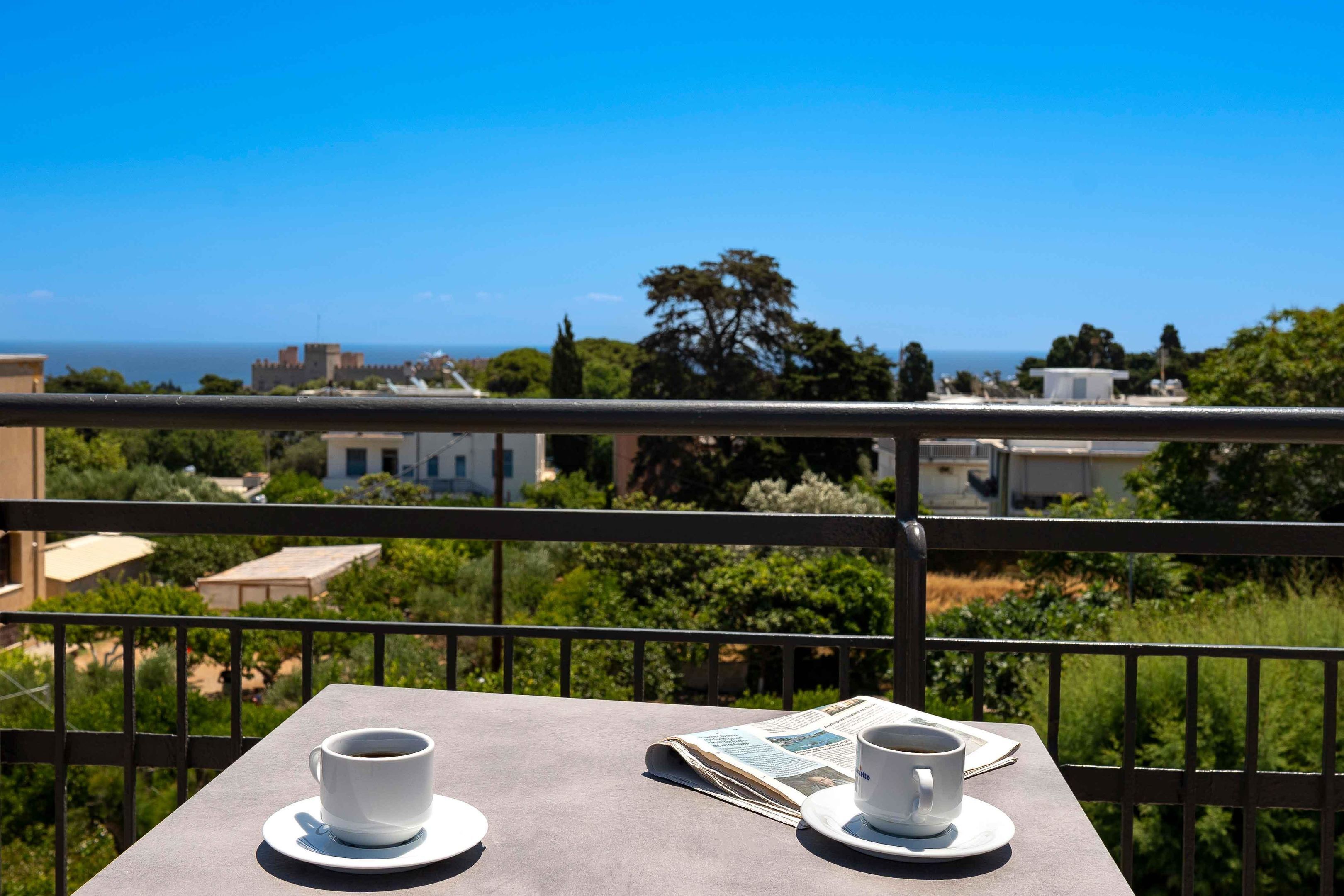 Un balcon avec une table, deux tasses de café et un journal.