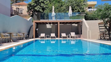 Una piscina al aire libre de temporada, sillones reclinables de piscina
