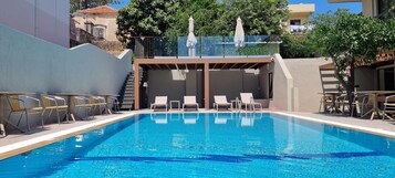 Una piscina al aire libre de temporada, tumbonas