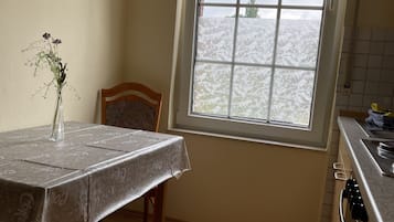 Una cocina con una mesa de comedor, un florero con flores y una ventana con vistas a un paisaje nevado.