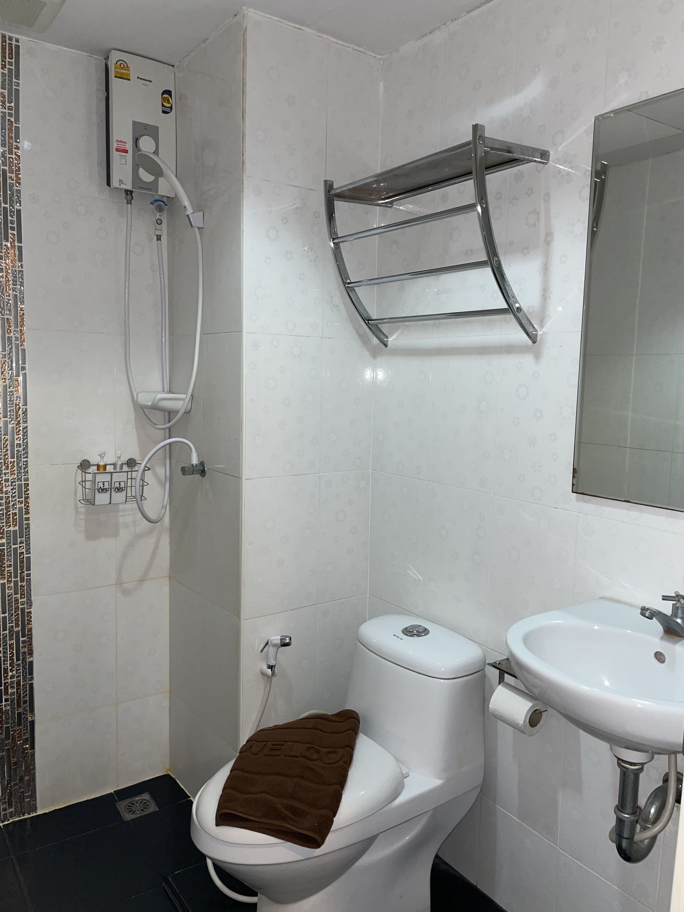 A bathroom with a toilet, a sink, a shower, and a towel rack.