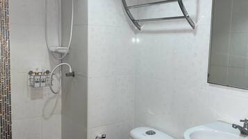 A bathroom with a toilet, a sink, a shower, and a towel rack.