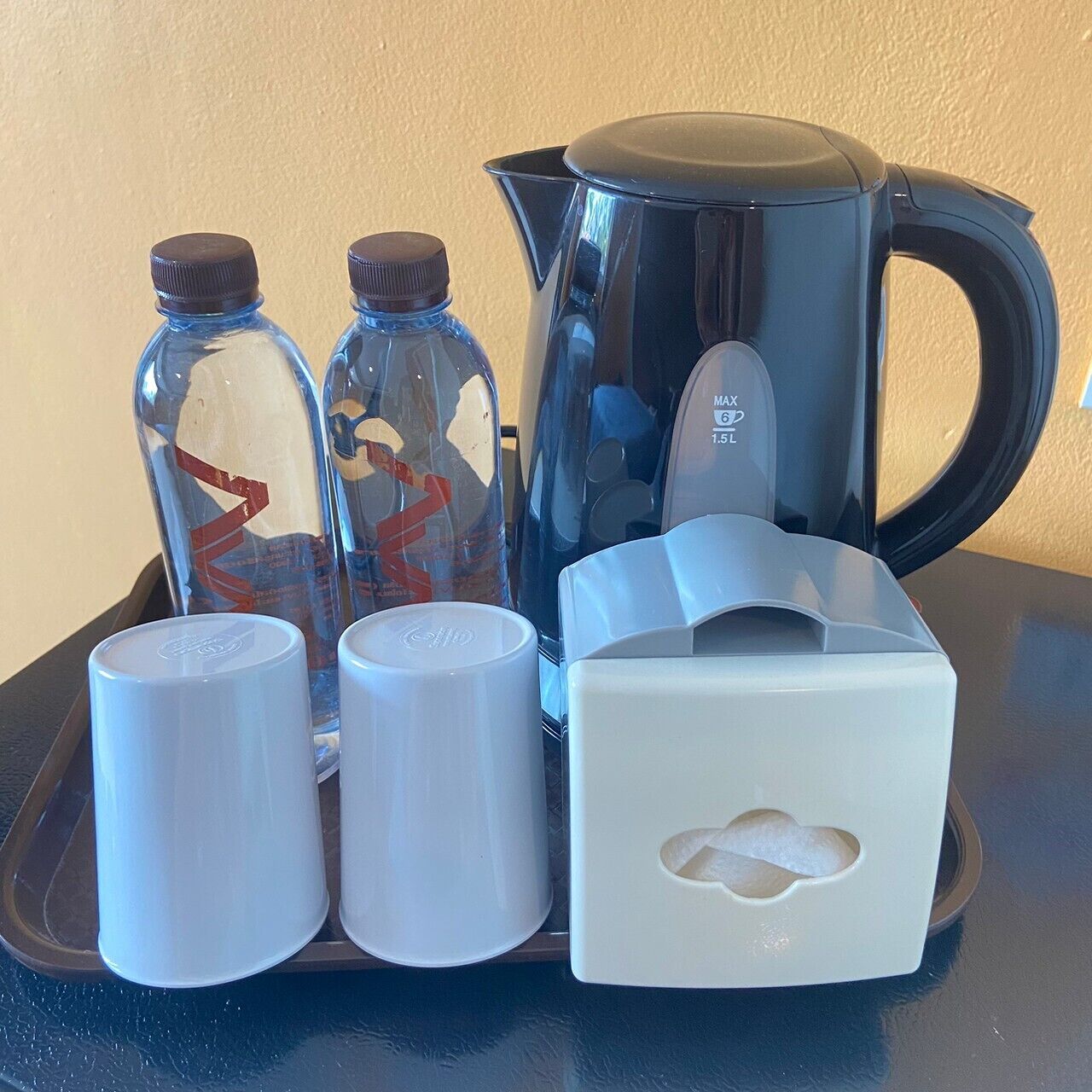 A tray with a black coffee pot, two glass bottles with brown caps, and two white containers.