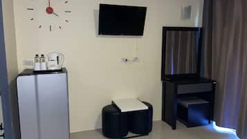 Et moderne hotelværelse med et fladskærms-tv på væggen, en minibar, et lille opholdsområde og et vindue med gardiner.