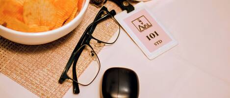 A bowl of chips, a pair of glasses, a computer mouse, and a tag with the number 101 on a table.