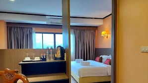 A hotel room with a bed, a desk with a coffee maker, and a view of the outdoors through the window. - M Hotel Danok (Sadao)