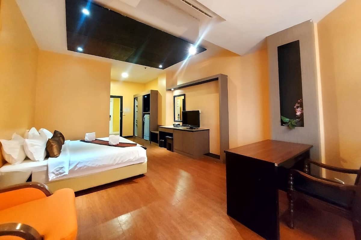A hotel room with a bed, desk, and a small seating area.