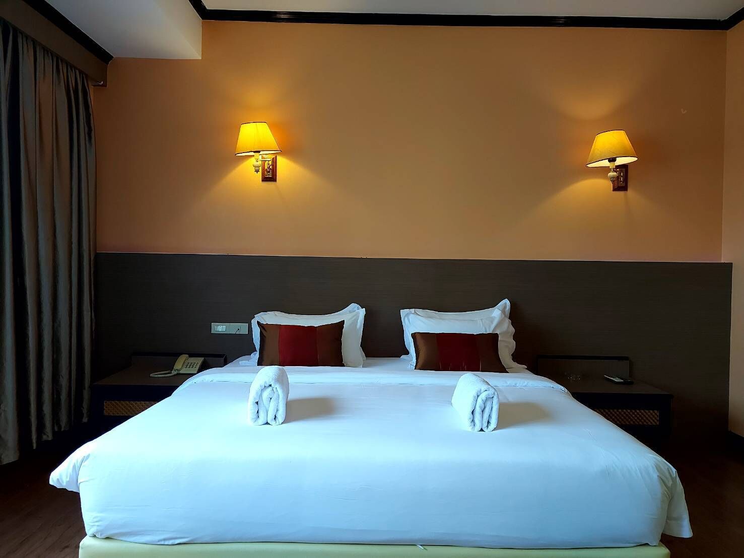 A hotel room with a large bed, two bedside tables, and two wall-mounted lamps.
