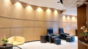 A modern lounge area with curved wooden panel walls, recessed ceiling lighting, and a decorative chandelier. - M Hotel Danok (Sadao)