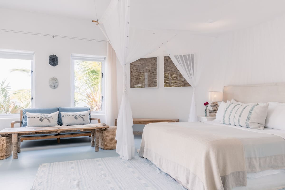 A bedroom with a bed, a bench, and a window.