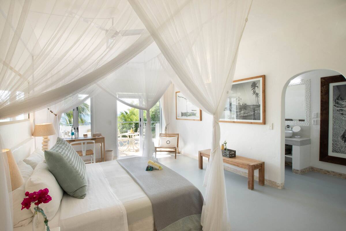A spacious bedroom with a canopy bed, a desk, and a view of the outdoors.