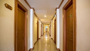 A hotel hallway with wooden doors, a sign indicating room number 102, and a fire extinguisher on the wall. - Loei Village Hotel (Mueang Loei)