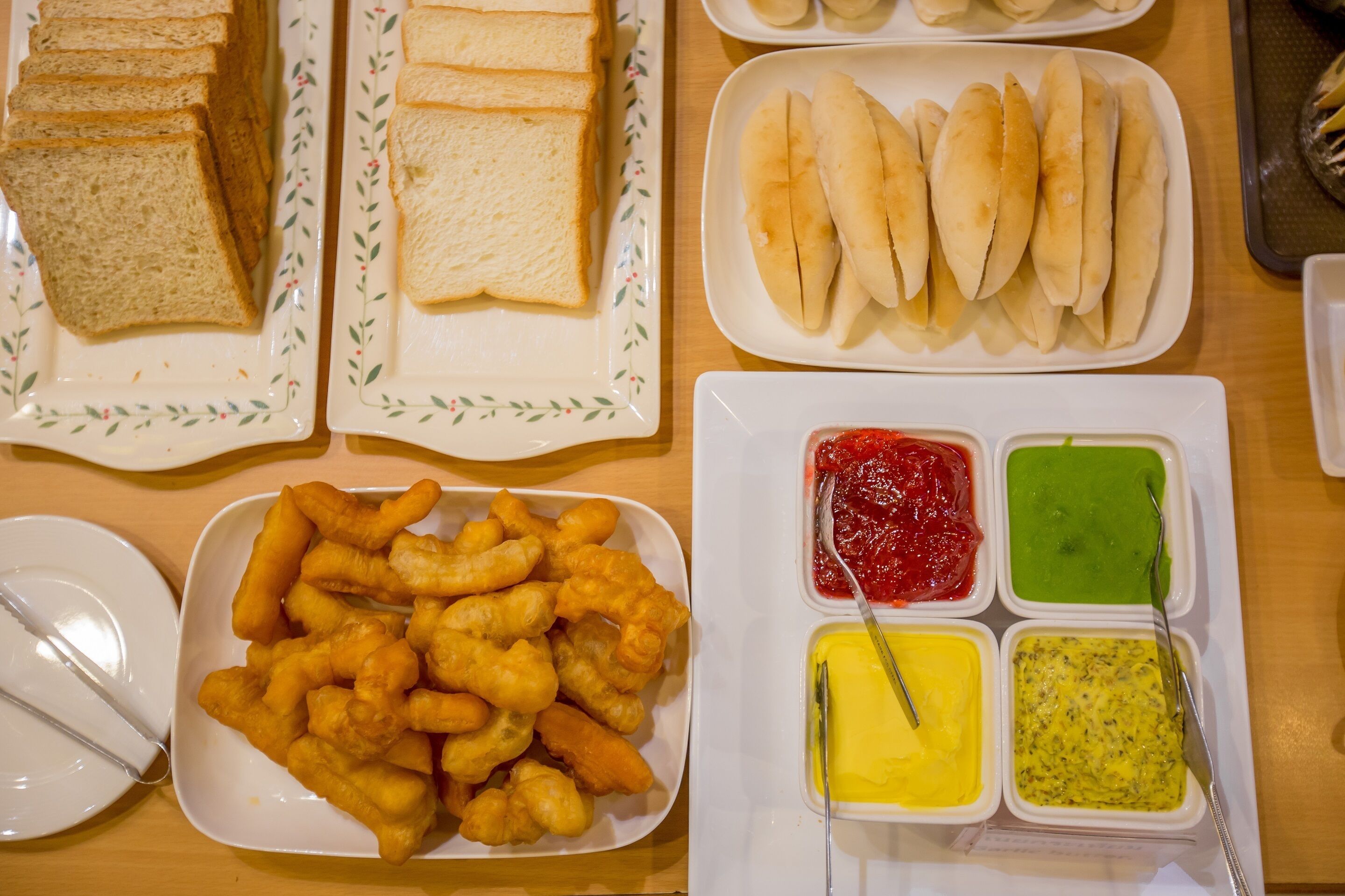 A table with various food items including bread, buns, and fried snacks, along with condiments.