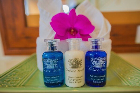 Tres botellas de productos de aromaterapia Nature Touch sobre una bandeja verde.