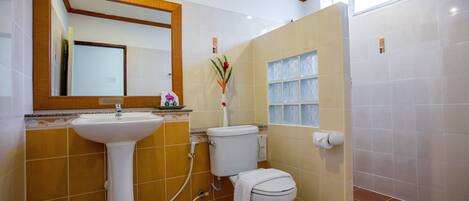 Un baño con lavamanos pedestal, inodoro y ventana con vidrio esmerilado.