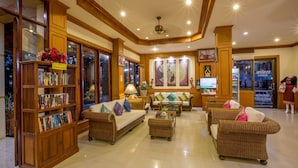 A spacious lobby with a large wooden bookshelf, comfortable seating areas, and a television. - Loei Village Hotel (Mueang Loei)