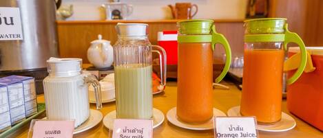 A beverage station with labeled containers of milk, soy milk, and orange juice.