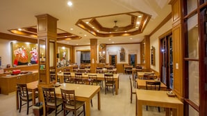 A spacious restaurant with wooden furniture and a high ceiling with geometric patterns. - Loei Village Hotel (Mueang Loei)