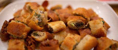 Un plato de comida con varios elementos, incluyendo lo que parecen ser masas fritas o bollos, posiblemente con carne y vegetales.