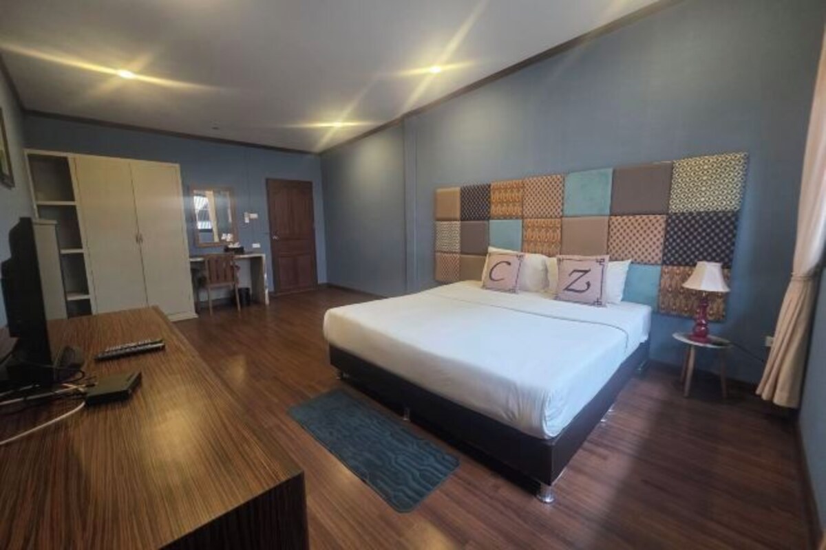 A modern bedroom with a large bed, a desk, and a wardrobe.