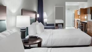 A hotel room with a large bed, bedside tables, a desk, and a bathroom visible through an open door. - Home2 Suites by Hilton Greenville Airport (Greenville)