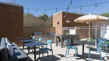 Un patio al aire libre con mesas, sillas y una parrilla.
