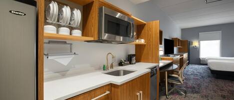 Una cocina moderna con microondas, horno y fregadero integrados. Hay una cafetera y un refrigerador pequeño en la encimera.