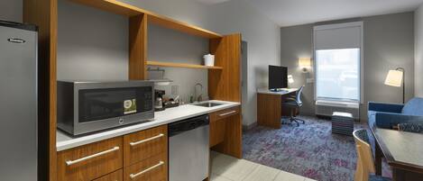 A modern kitchen with a built-in microwave, a dishwasher, wooden cabinets, and a dining area with a table and chairs.