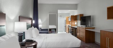 Habitación de hotel con dos camas, un escritorio, televisión y kitchenette.