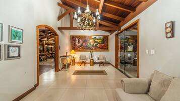 A spacious living area with a chandelier, a painting, and a sofa.