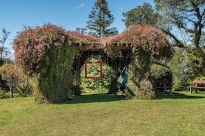 A garden with a wooden pergola covered in flowering vines. - Hotel Bangalôs da Serra (Gramado)