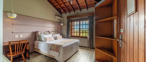 A bedroom with a wooden ceiling, a bed with floral bedding, a wooden chair, and a window with a view.