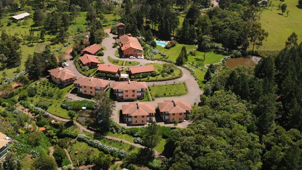 An aerial view of a residential area with multiple houses, a swimming pool, and well-maintained gardens. - Hotel Bangalôs da Serra (Gramado)