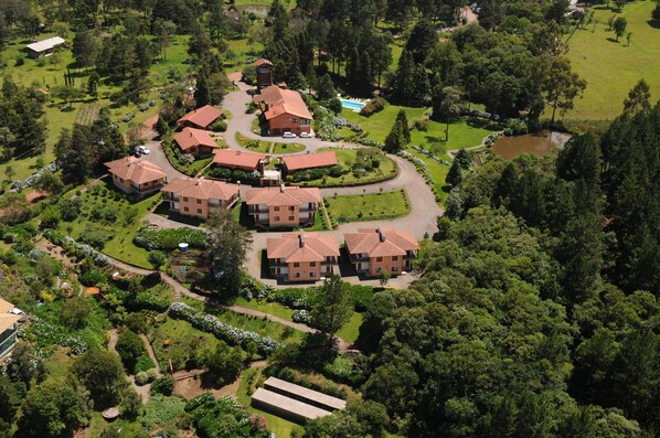 An aerial view of a residential area with multiple houses, a swimming pool, and well-maintained gardens. - Hotel Bangalôs da Serra (Gramado)