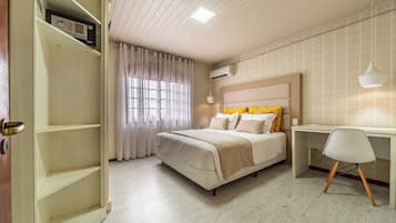 Un dormitorio con cama, escritorio y silla. Hay un armario y un equipo de aire acondicionado en la pared.