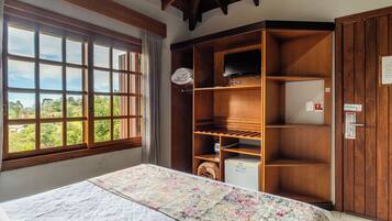 Een kamer met een bed, een groot raam, een kledingkast en een televisie.