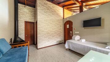 Quarto com cama, sofá, televisão na parede e teto de madeira.