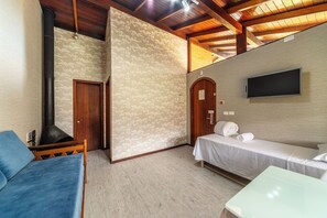 Una habitación con una cama, un sofá, un televisor montado en la pared y techo de madera.