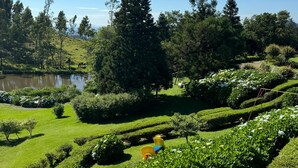 A well-maintained garden with a pond, neatly trimmed hedges, and a variety of trees. - Hotel Bangalôs da Serra (Gramado)