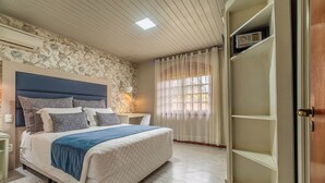 A bedroom with a bed, a nightstand, a wardrobe, a window with curtains, and a ceiling light. - Hotel Bangalôs da Serra (Gramado)