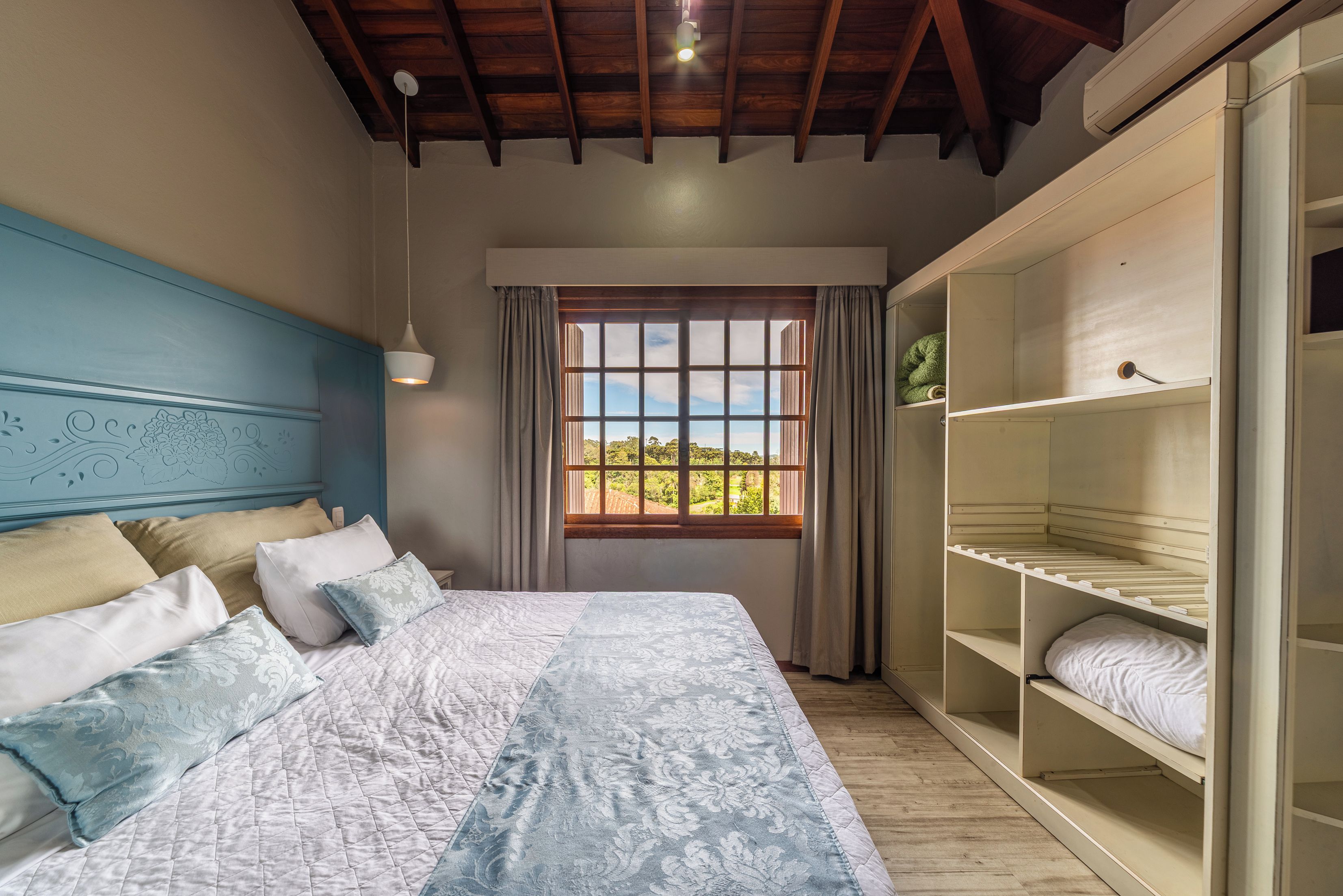 A bedroom with a bed, a window with curtains, a wardrobe, and a ceiling fan.