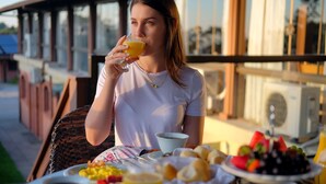 A person seated at an outdoor table with a meal, including bread, fruit, and a beverage. - Hotel Bangalôs da Serra (Gramado)