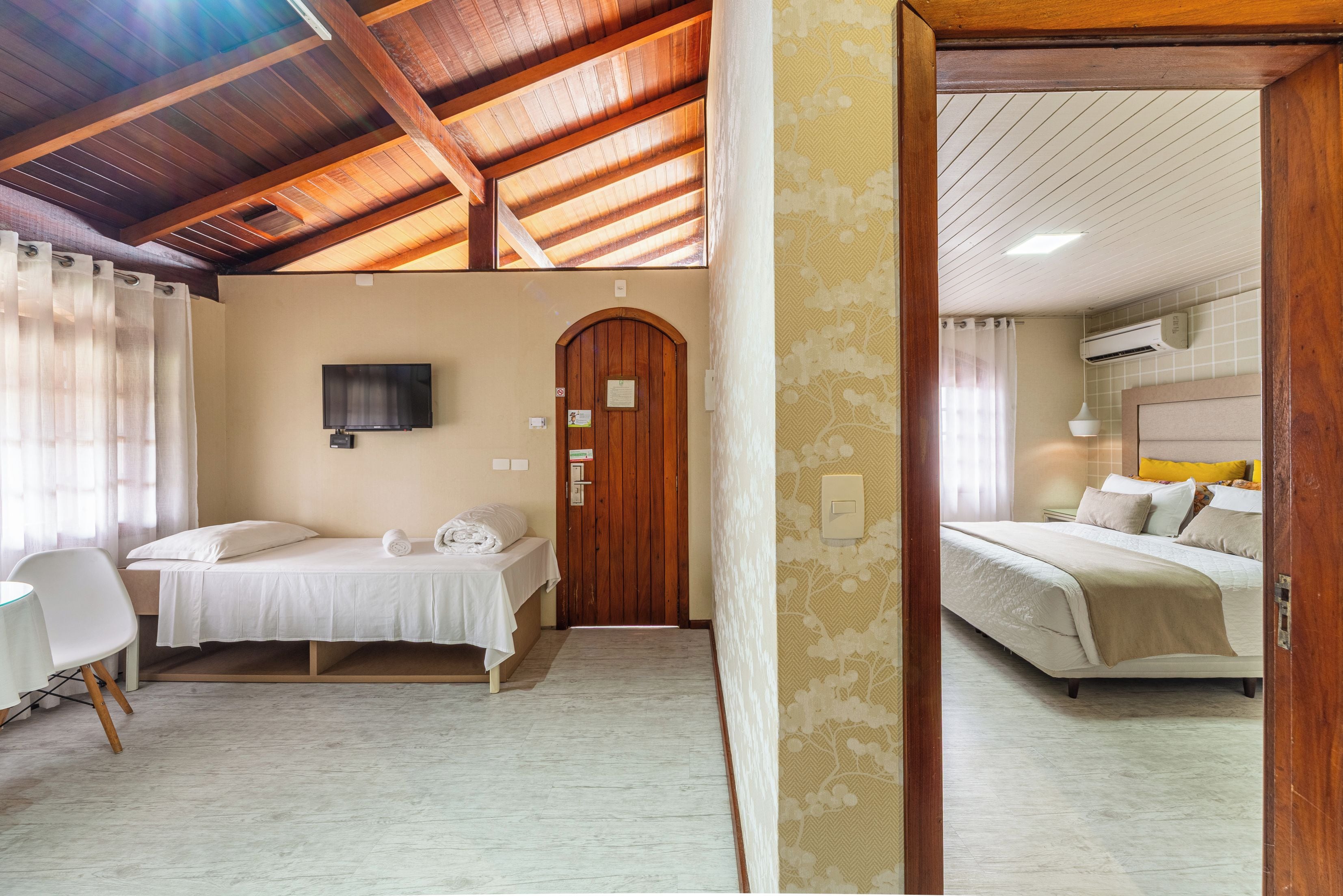 Een hotelkamer met twee bedden, een televisie, een houten deur en een plafond met houten balken.
