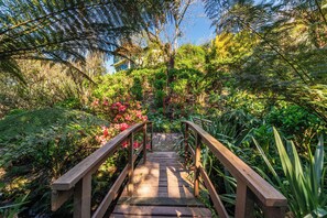Un puente de madera que atraviesa un exuberante jardín con follaje denso y plantas en flor.