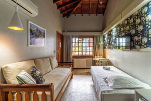 A room with a wooden ceiling, a sofa, a bed, a small table, and a wall-mounted TV. - Hotel Bangalôs da Serra (Gramado)