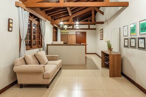 Un salón acogedor con un sofá, una mesa de centro de madera y una mesita auxiliar con un florero.